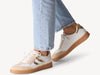 Women's laced fashion sneaker featuring a classic design, gold accents, and a comfortable subtle platform sole, model view